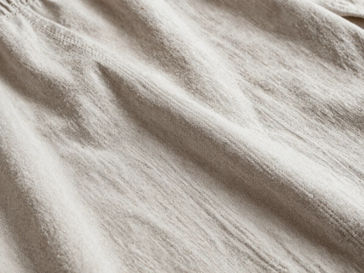 Editorial apparel photography, close detail study of a woven textile garment, soft balanced daylight, tactile neutral to